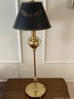 Full view of brass urn-form lamp with black shade