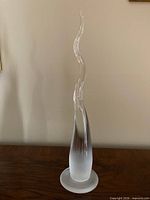 Full view of clear glass flame sculpture on wooden surface