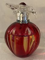 Front view of red glass perfume bottle with Cartier collar and clear floral cap