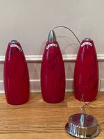 Three red glass pendant fixtures with one ceiling canopy displayed