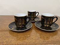 three cups on saucers showing gold landscape designs