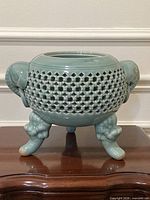 Front view showing complete vase, reticulated body, elephant handles, tripod feet