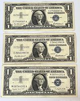 Obverse of three $1 silver certificates stacked showing serials and blue seals