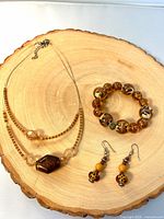 Full view of necklace, bracelet, earrings on wood slab