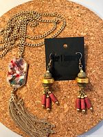 Earrings on card and necklace laid on cork surface