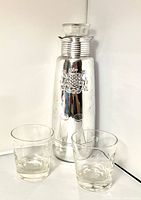 Carafe with lid flanked by two tumblers