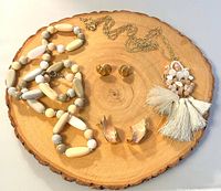 Group shot of both necklaces, both earring pairs on wood slab