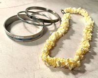 Three bangles and shell necklace displayed on surface