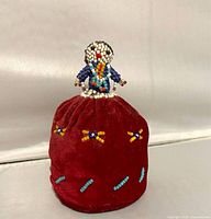 Front view showing beaded doll on burgundy velvet base
