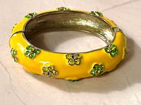 oblique view of yellow enamel bangle showing rhinestone flowers