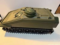 Left side view of olive green APC showing turret hatch, hull detailing, and tracks