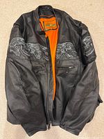 Front view showing black leather shell, orange lining, skull embroidery, zipper closure
