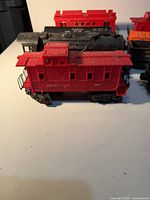 Red caboose 1007 with black tender and partial orange hopper visible