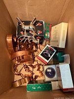 Overview of lot in box showing copper cookie cutters, Hallmark boxes, metal cutter, purple ornament