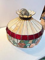 Full view of stained glass pendant lamp showing cream ribs, red band, floral motif, metal crown