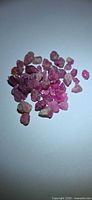 Pile of small pink raw ruby crystals on white background