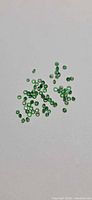 Loose green tsavorite garnet stones spread on surface