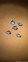 Five pear-cut aquamarines on a brown surface