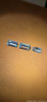 Three rectangular step-cut aquamarines on tan surface