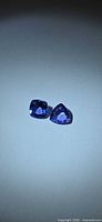 Both violet-blue tanzanite stones side by side on neutral background