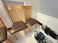 Two matching wooden chairs with brown cushions shown together