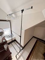 Full view of garment rack showing chrome top rail, black frame, casters, and hangers