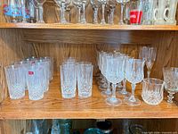 Shelf with groups of highball glasses, tumblers, wine goblets and footed bowl