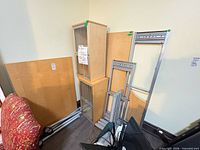 Overall view of disassembled cupboards, desk panel, and metal frames leaning against wall