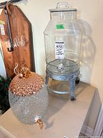 Both glass beverage dispensers side by side on surface