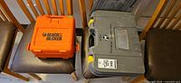Mastercraft gray case and Black & Decker orange case on chairs
