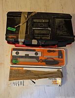 Black taped toolbox stacked on red Mastercraft toolbox, orange woodworking tool set and HDX tile cutter box visible