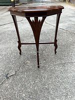 Front view of carved wood end table showing legs and stretcher