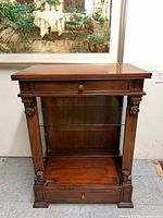 Front view of wooden display cabinet showing glass shelf and drawer handles