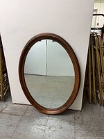 Full view of walnut oval mirror resting against wall