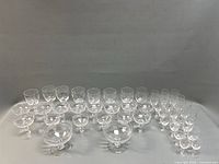 Group of 34 laurel etched stem glasses displayed