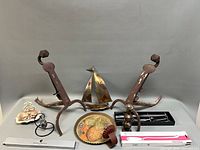 Group shot of all items including andirons, sailboat, cutlery, soap dish, pepper mill box, utensil box, candle holder, glass ornament on stand