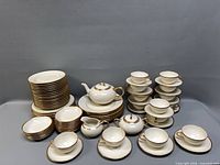 Full view of stacked plates, bowls, cups, saucers, teapot, creamer and sugar bowl