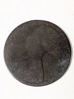 Obverse side of heavily worn copper coin