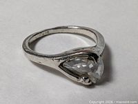 Side view of silver plated ring showing clear faceted stone and band wear