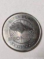 Obverse of coin showing Broncos logo and Super Bowl inscription