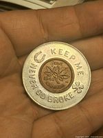 Front showing 1948 maple-leaf cent within aluminum ring stamped “KEEP ME NEVER GO BROKE” with horseshoe and shamrock