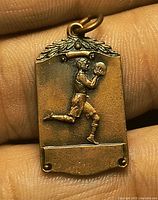 Front of bronze pendant showing athlete relief and laurel top