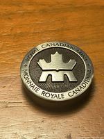 Front of round pewter emblem showing Royal Canadian Mint logo and bilingual text