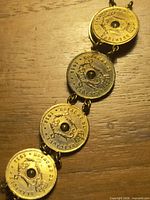 Five-coin gold-plated bracelet segment showing coin detail and faux gemstone