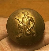 Front view of brass button showing kneeling soldier with rifle