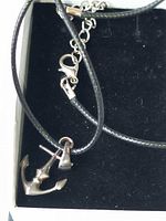 Anchor pendant and part of leather cord inside box