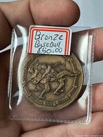 Medallion in plastic flip displaying obverse with two players