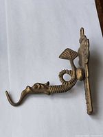 Side view of bronze dragon hook showing profile and backplate
