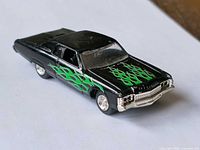 Front/side view of black die-cast car with green flames