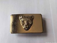 Front view of rectangular gold buckle with leopard head motif